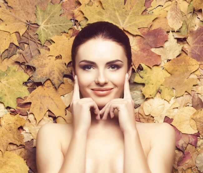 trattamenti-viso-autunno Donna dal viso curato con sfondo di foglie autunnali.